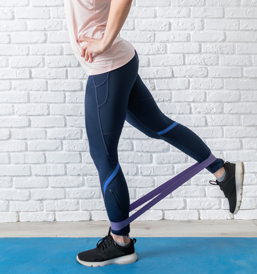 woman exercising legs at home using rubber resistance band